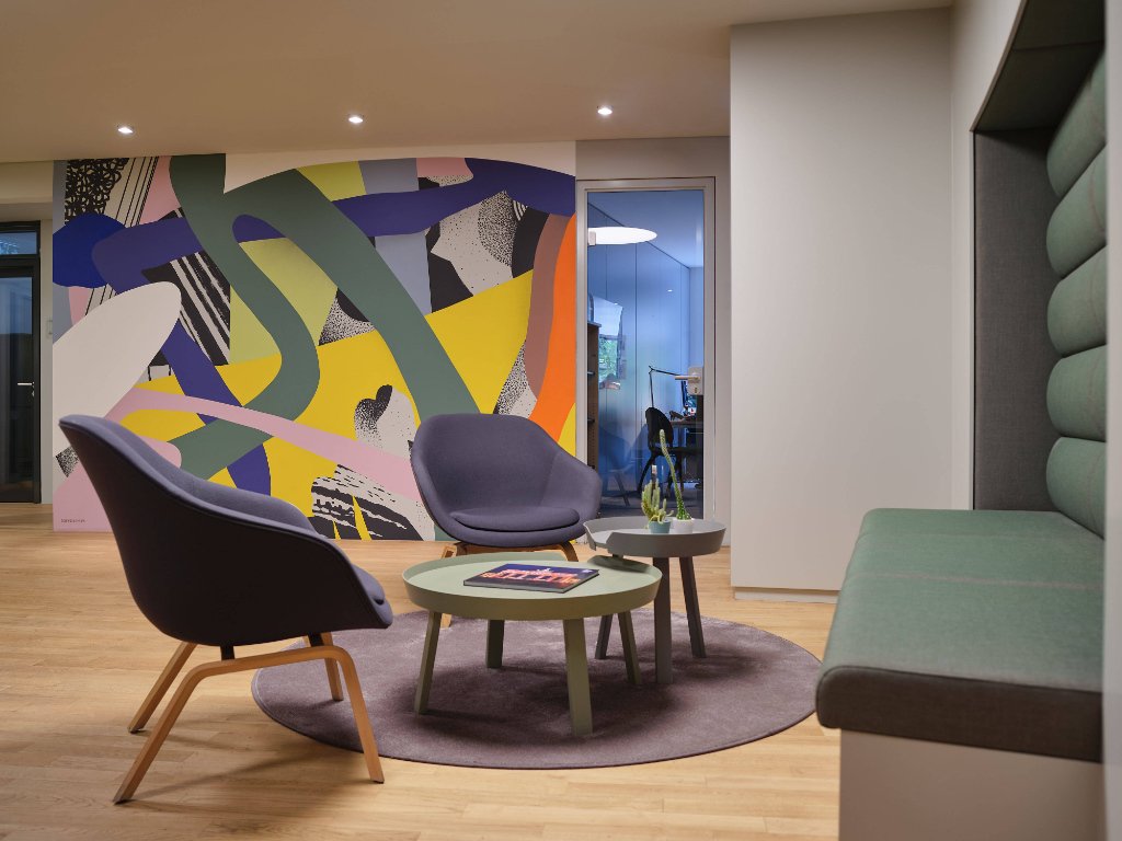 business-space-berlin-lobby-1 zwei-graue-stuehle-vor-bunt-bemalter-wand